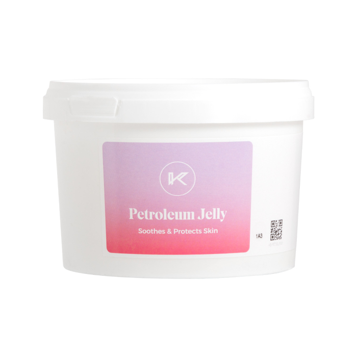 Un tube en plastique blanc avec couvercle à vis blanc, étiqueté Vaseline Killer Beauty Petroleum Jelly 500 ml, présenté dans un emballage à dégradé rose et violet, avec la mention « Soothing & Protects Skin » (Apaise et protège la peau).
