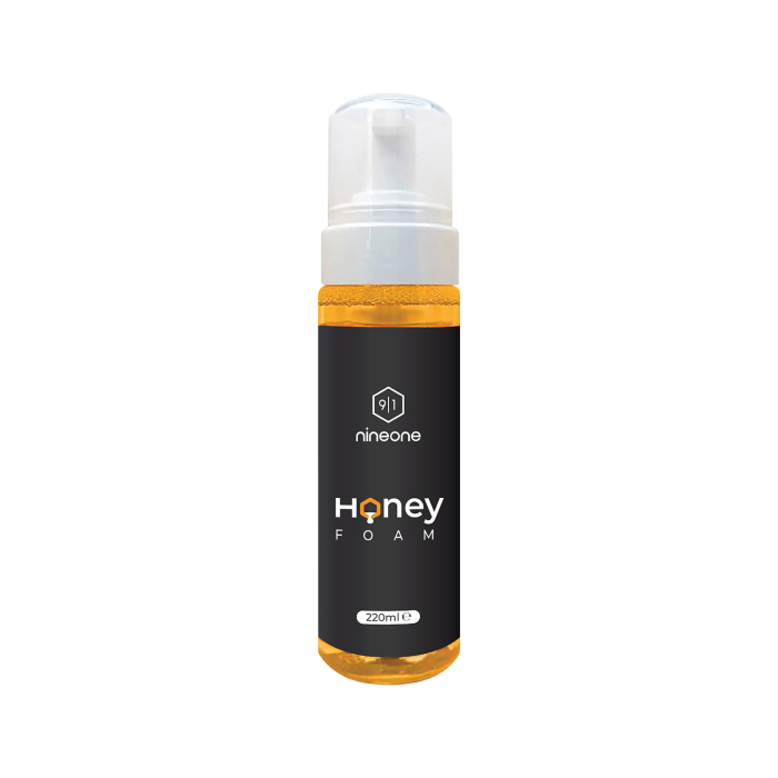 Un flacon en plastique transparent muni d’un distributeur à pompe blanc, contenant 220 ml de liquide jaune-orangé, étiqueté « Nineone Mousse au Miel » sur une étiquette noire.